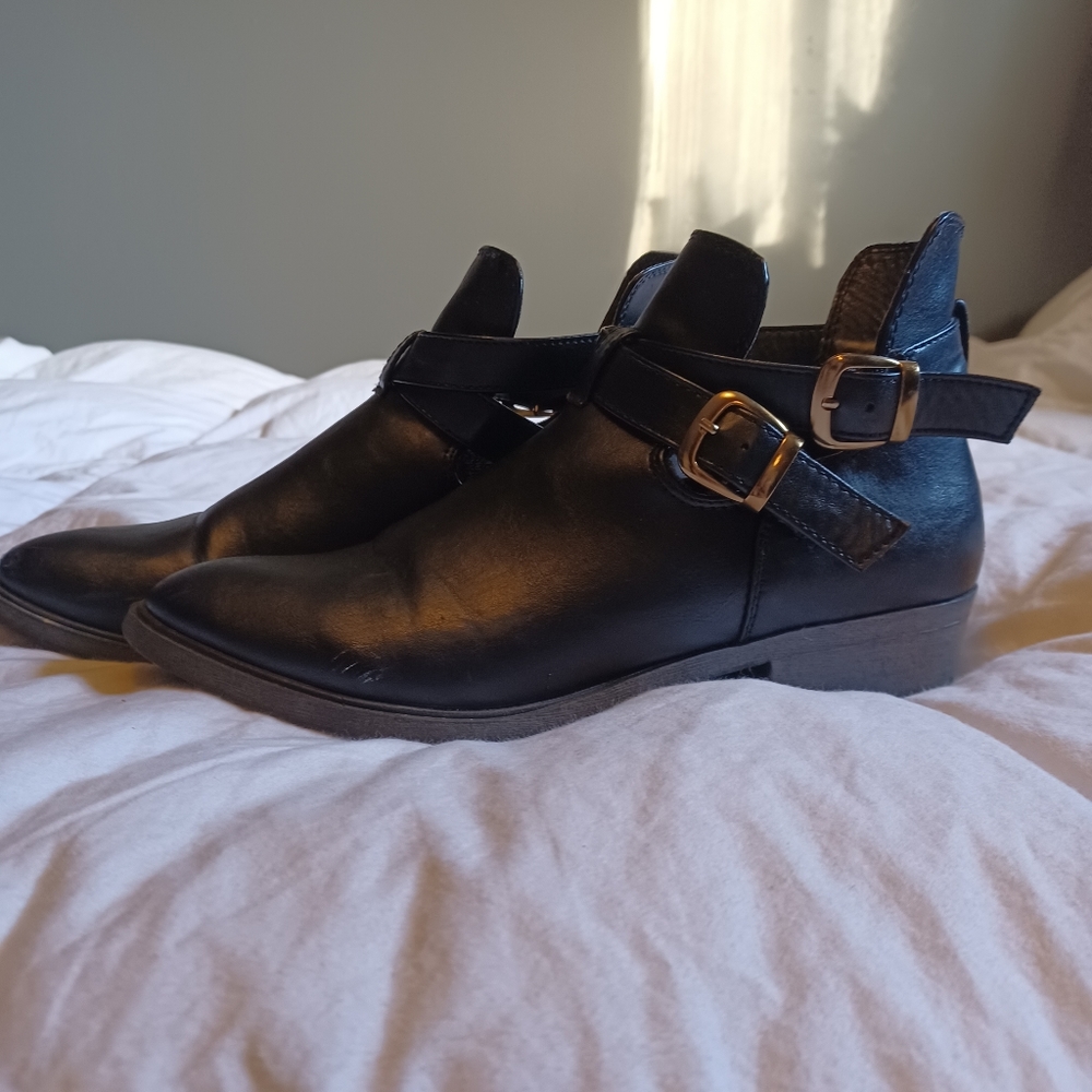 Black ankle boots with buckle features gold buckles